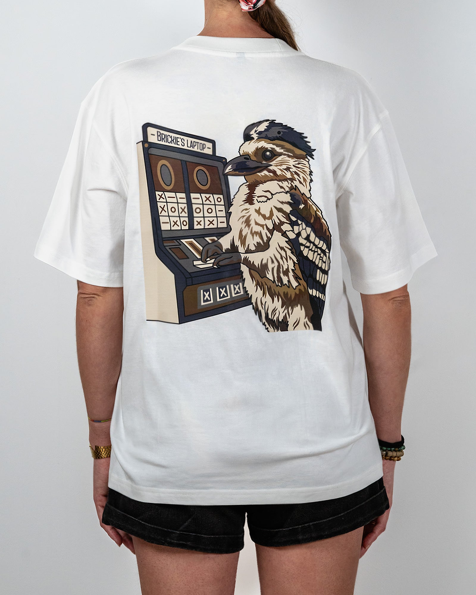 White t-shirt with a graphic of a bird and slot machine on the back, worn by a person and with the words "Brickie's Laptop".