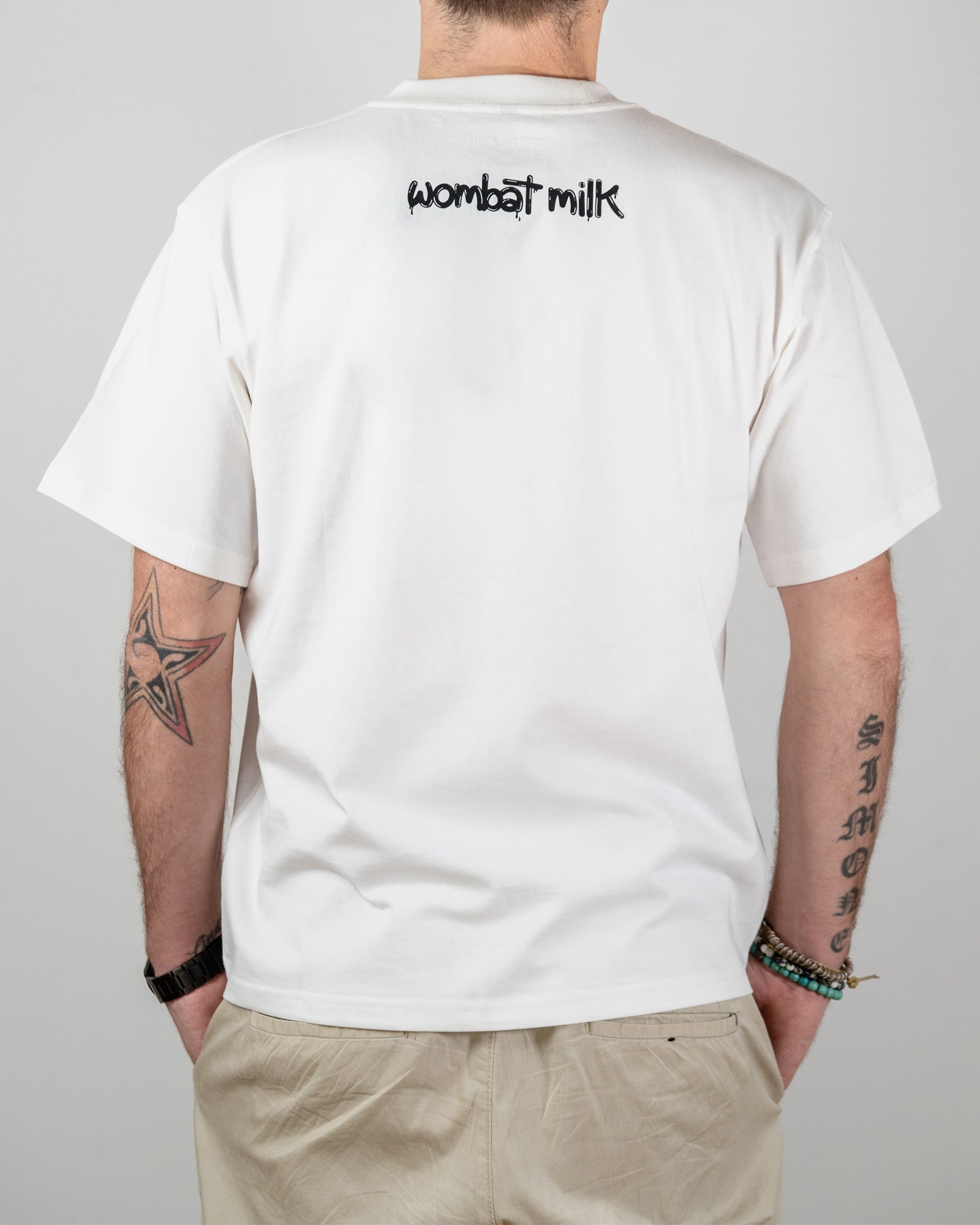 Person wearing a white t-shirt with 'wombat milk' text on the back, standing against a plain background.