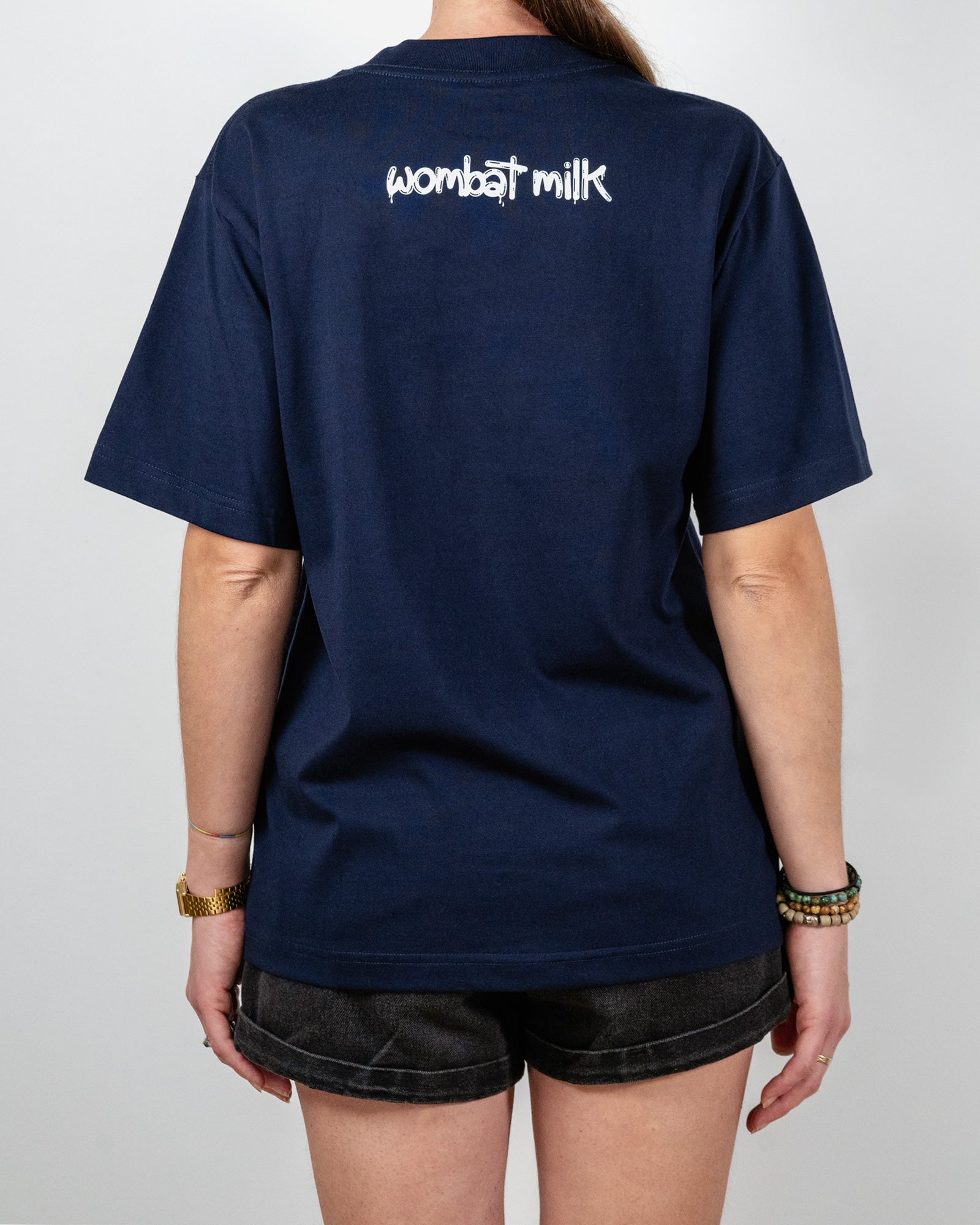 Navy blue t-shirt with 'wombat milk' text on the back, worn by a person.
