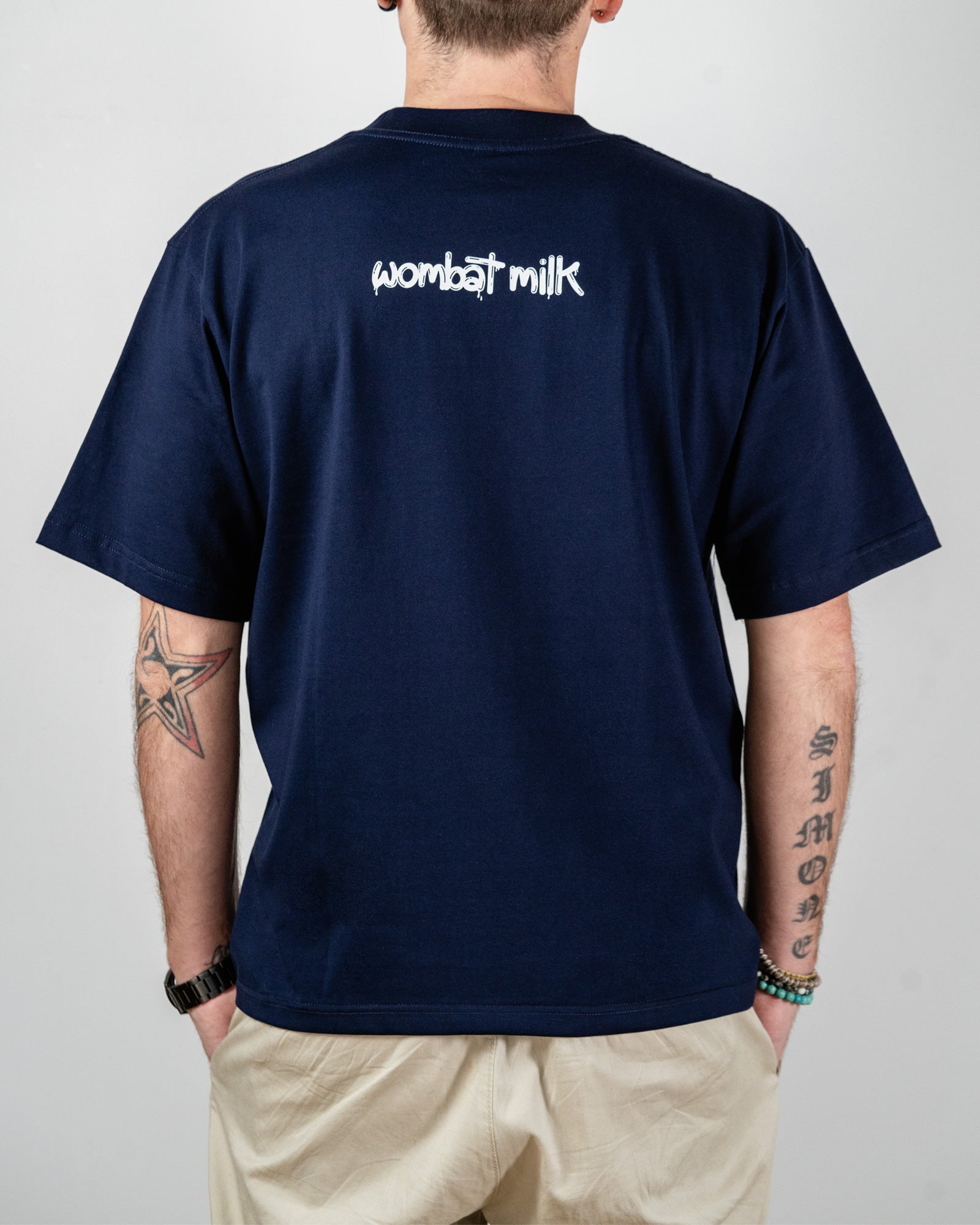 Navy blue t-shirt with 'wombat milk' text on the back, worn by a person.
