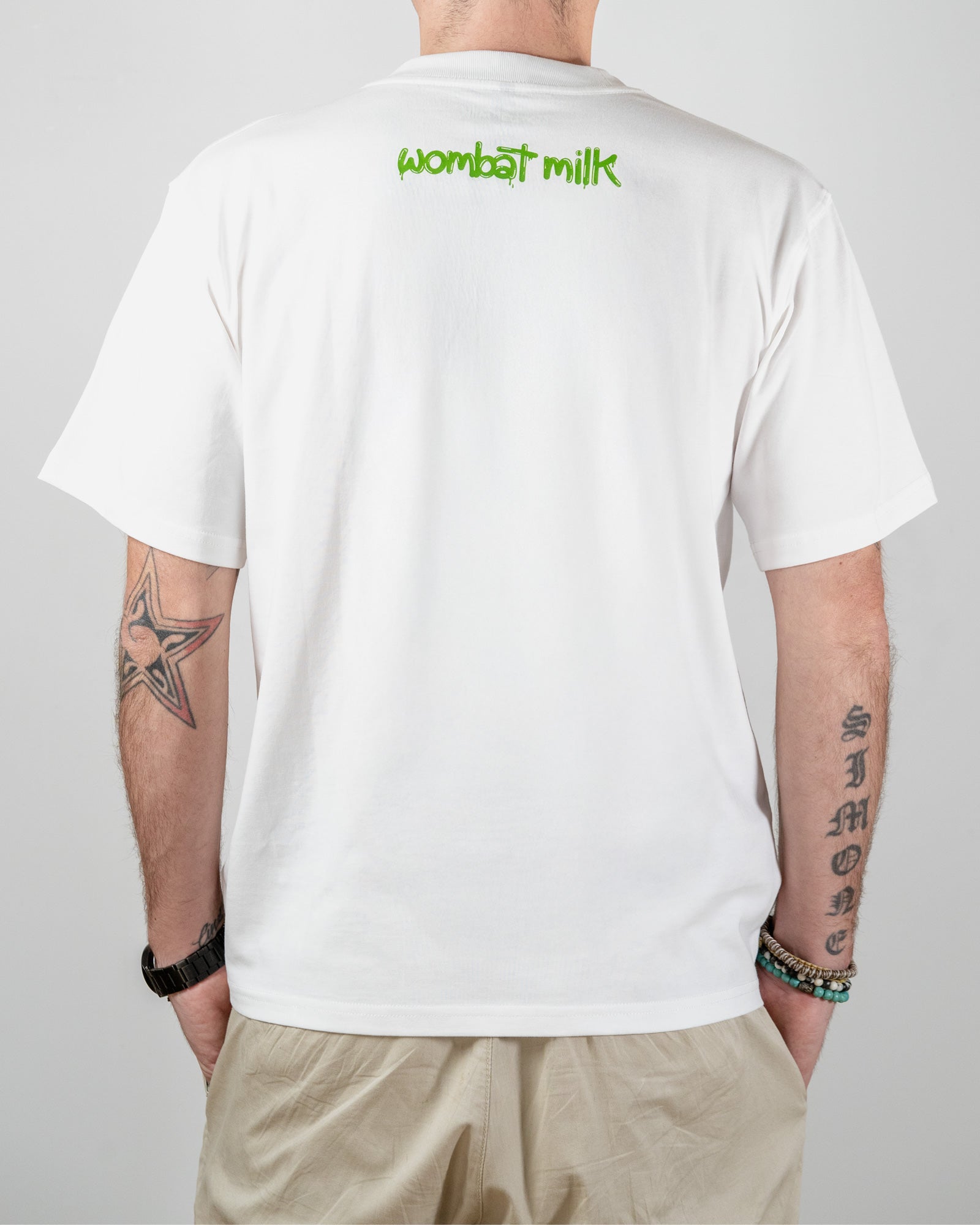 Person wearing a white t-shirt with 'wombat milk' text on the back, standing against a plain background.