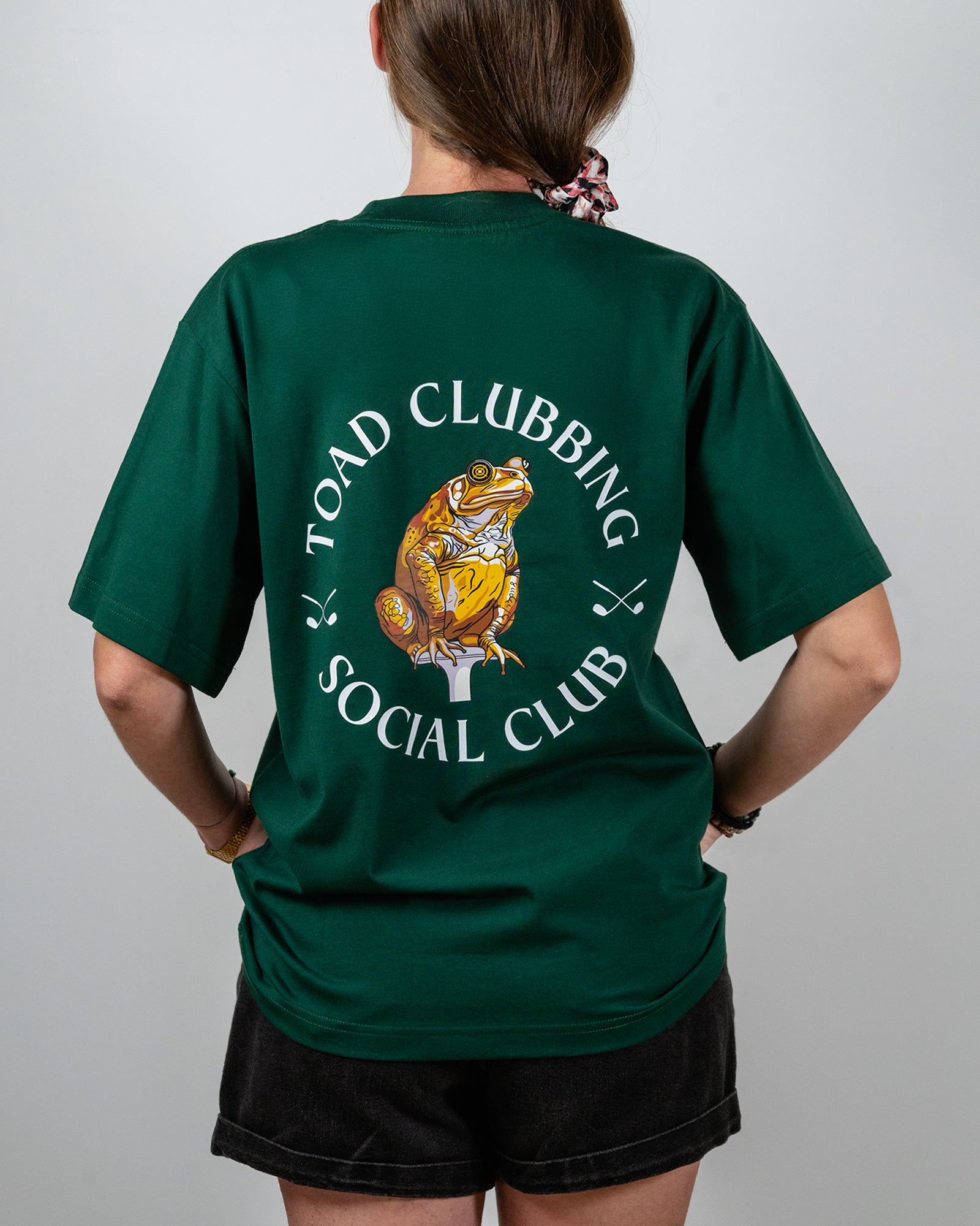 Person wearing a green t-shirt with 'Toad Clubbing Social Club' design on the back.