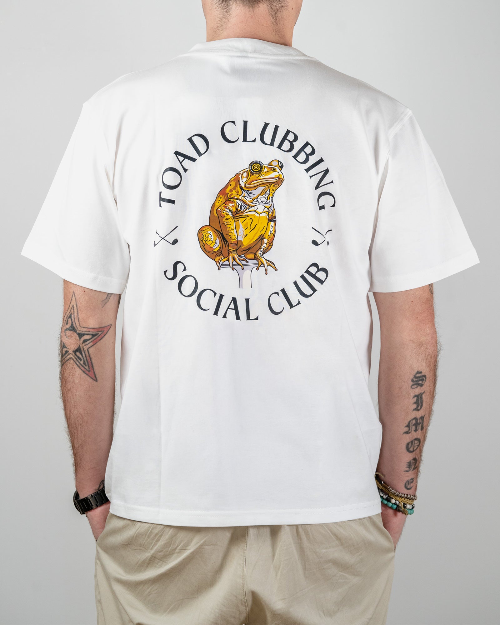 Person wearing a white t-shirt with a graphic of a toad and text on the back, standing against a plain background.