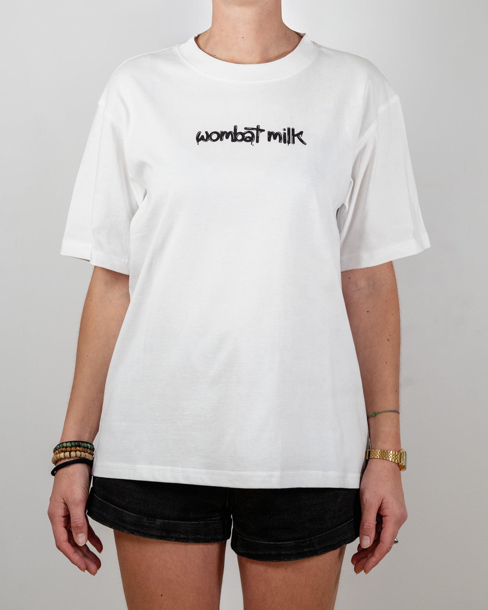 Person wearing a white t-shirt with 'wombat milk' text standing against a plain background.