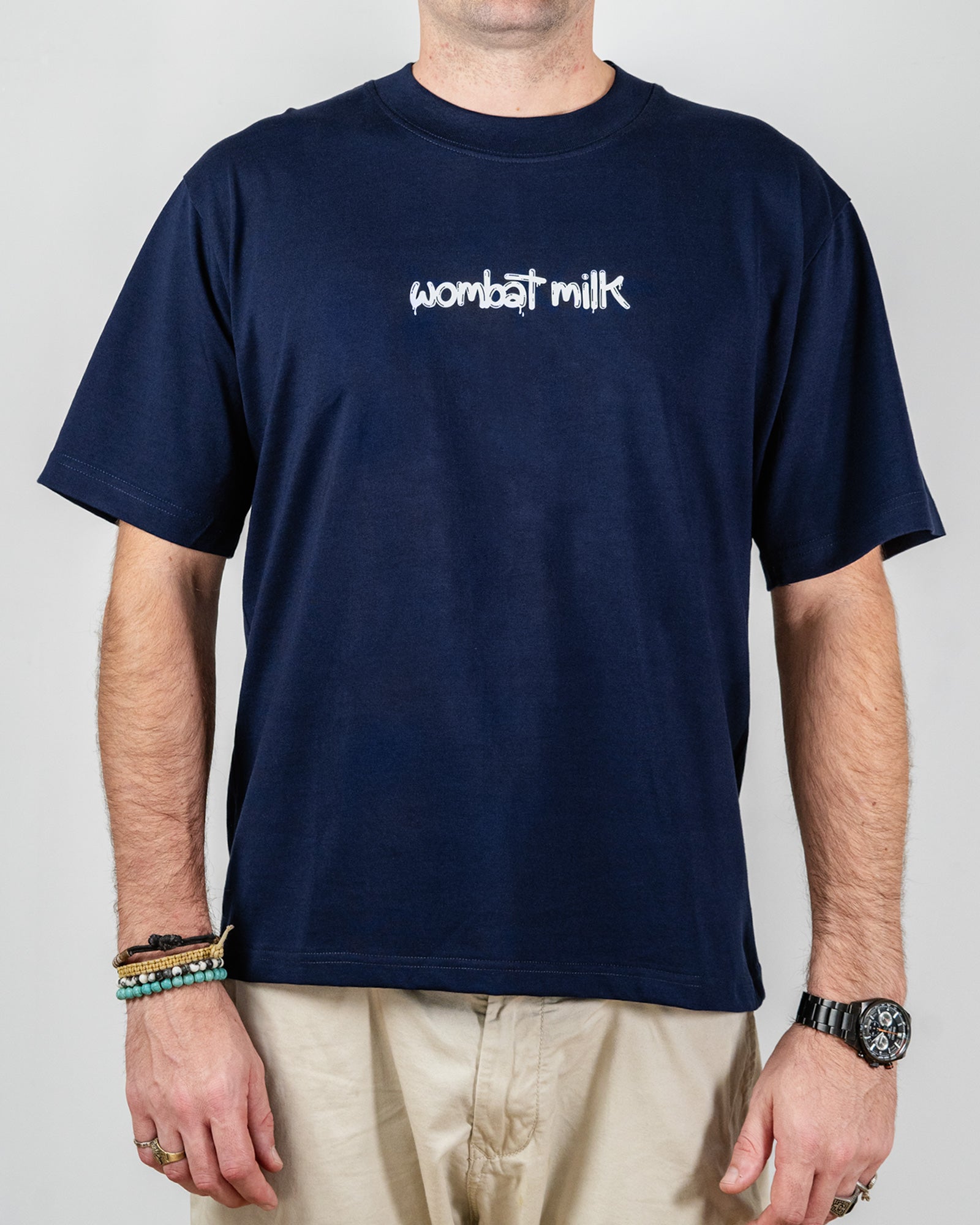 Person wearing a navy blue t-shirt with 'wombat milk' text standing against a plain background.