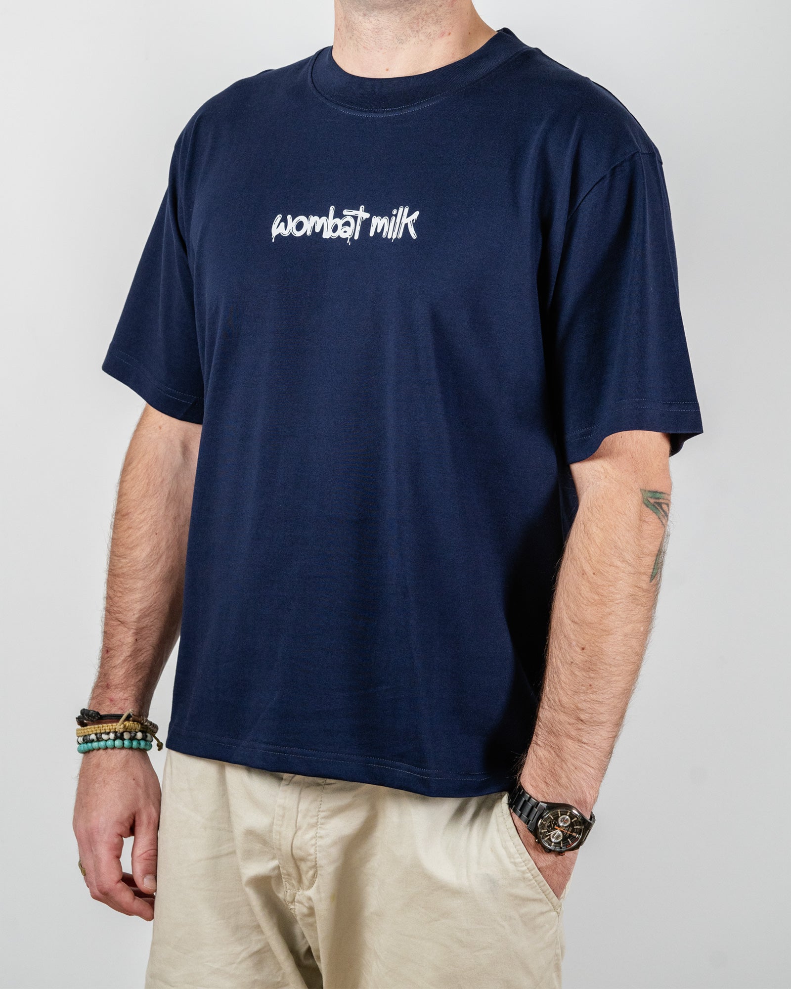 Person wearing a navy blue t-shirt with 'wombat milk' text standing against a plain background.