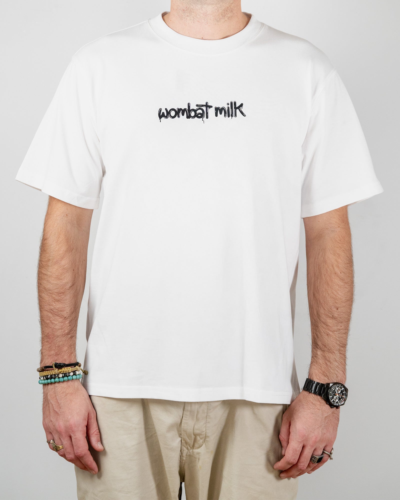 Person wearing a white t-shirt with 'wombat milk' text standing against a plain background.
