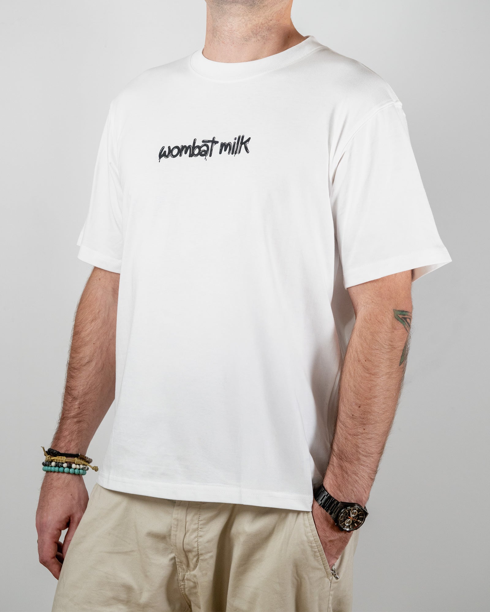 Person wearing a white t-shirt with 'wombat milk' text standing against a plain background.