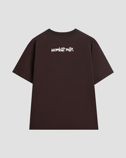 Brown t-shirt with 'wombat milk' text against a light grey background.