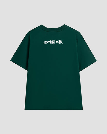 Green t-shirt with 'wombat milk' text against a light grey background.