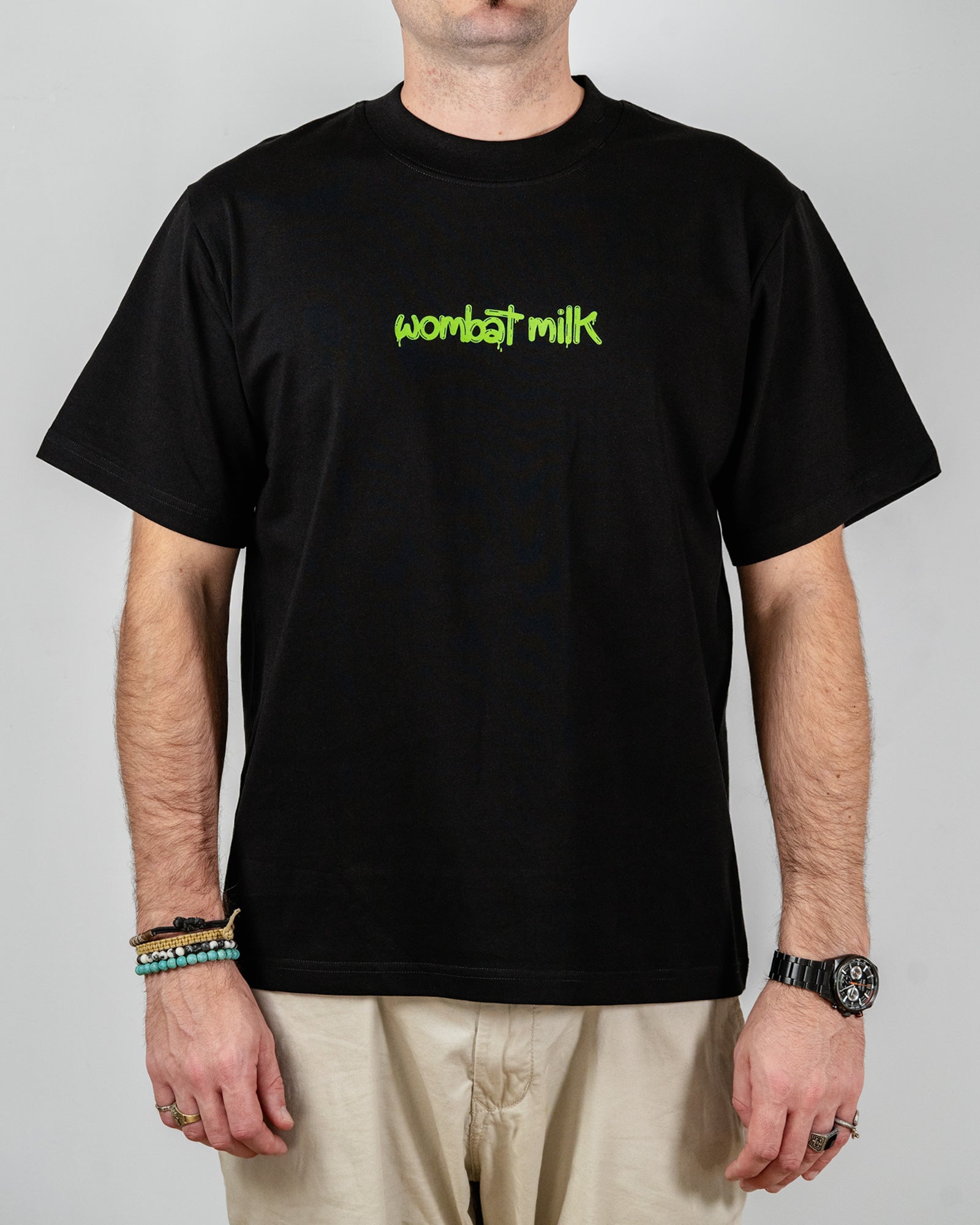 Person wearing a black t-shirt with 'wombat milk' text standing against a plain background.
