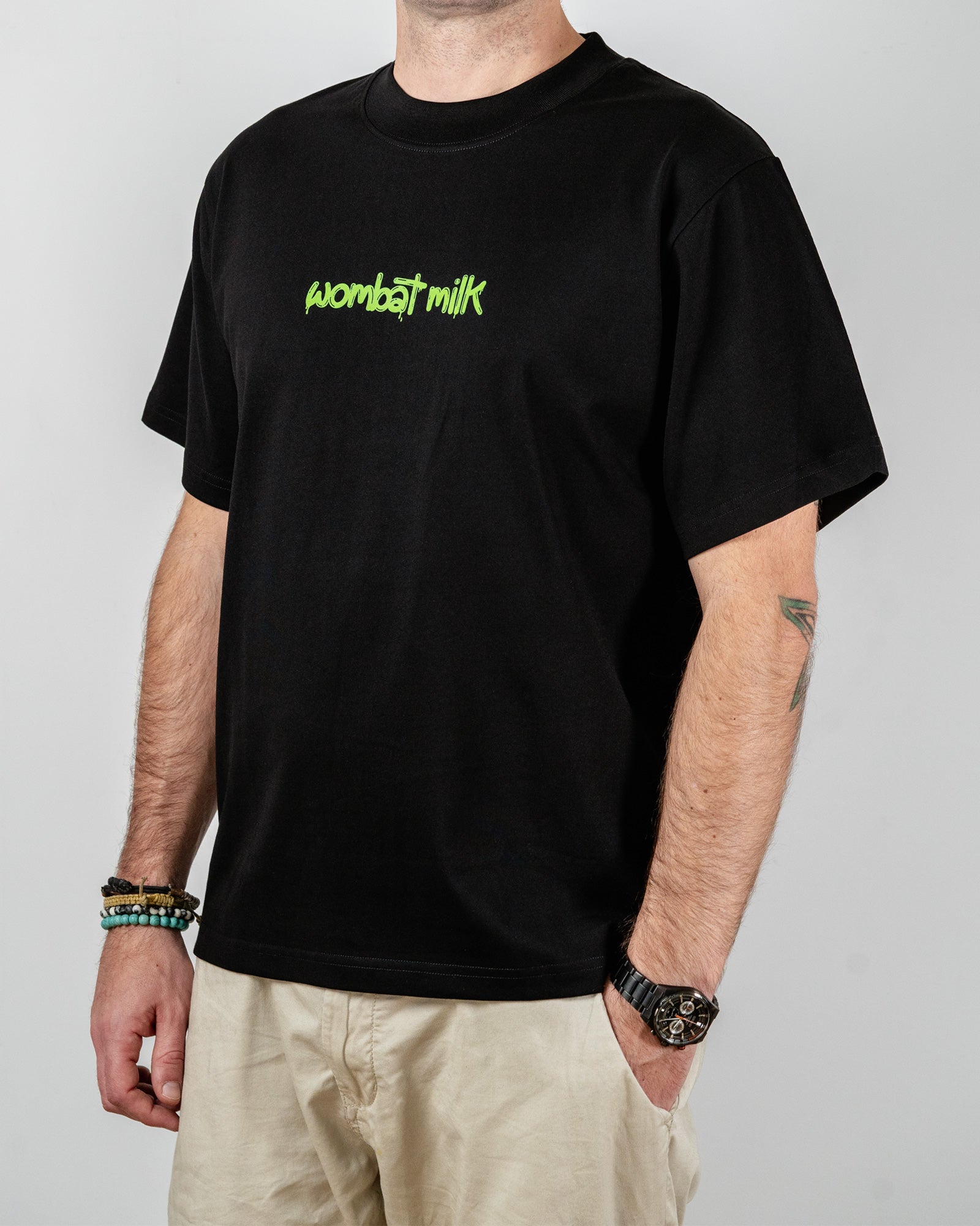 Person wearing a black t-shirt with 'wombat milk' text standing against a plain background.