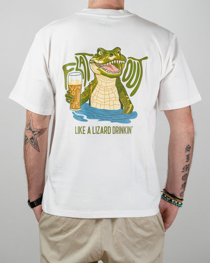 Person wearing a white t-shirt with a graphic of a crocodile drinking beer and text on the back that says 'Flat Out Like A Lizard Drinkin'.