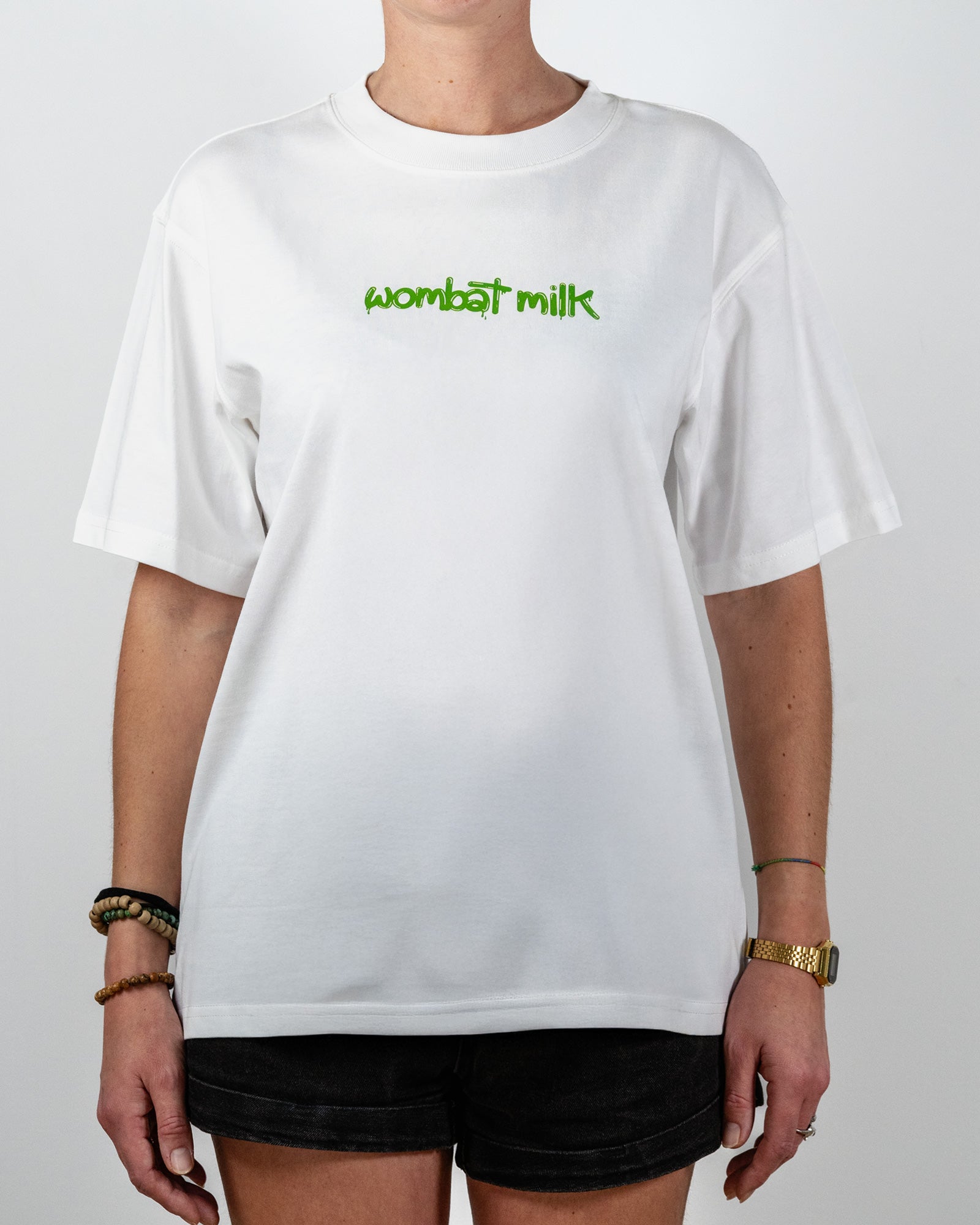 Person wearing a white t-shirt with 'wombat milk' text standing against a plain background.
