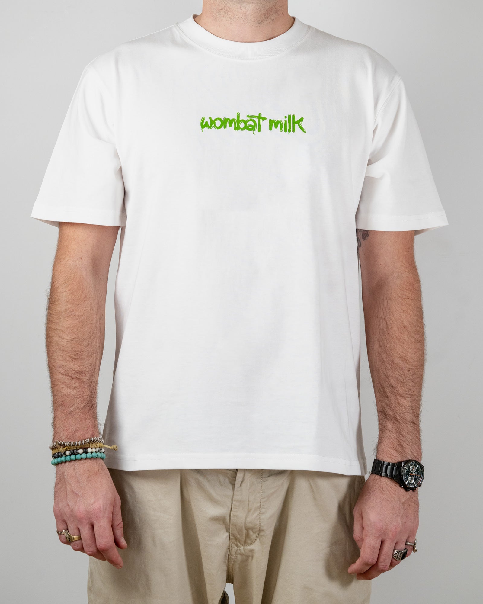 Person wearing a white t-shirt with 'wombat milk' text standing against a plain background.