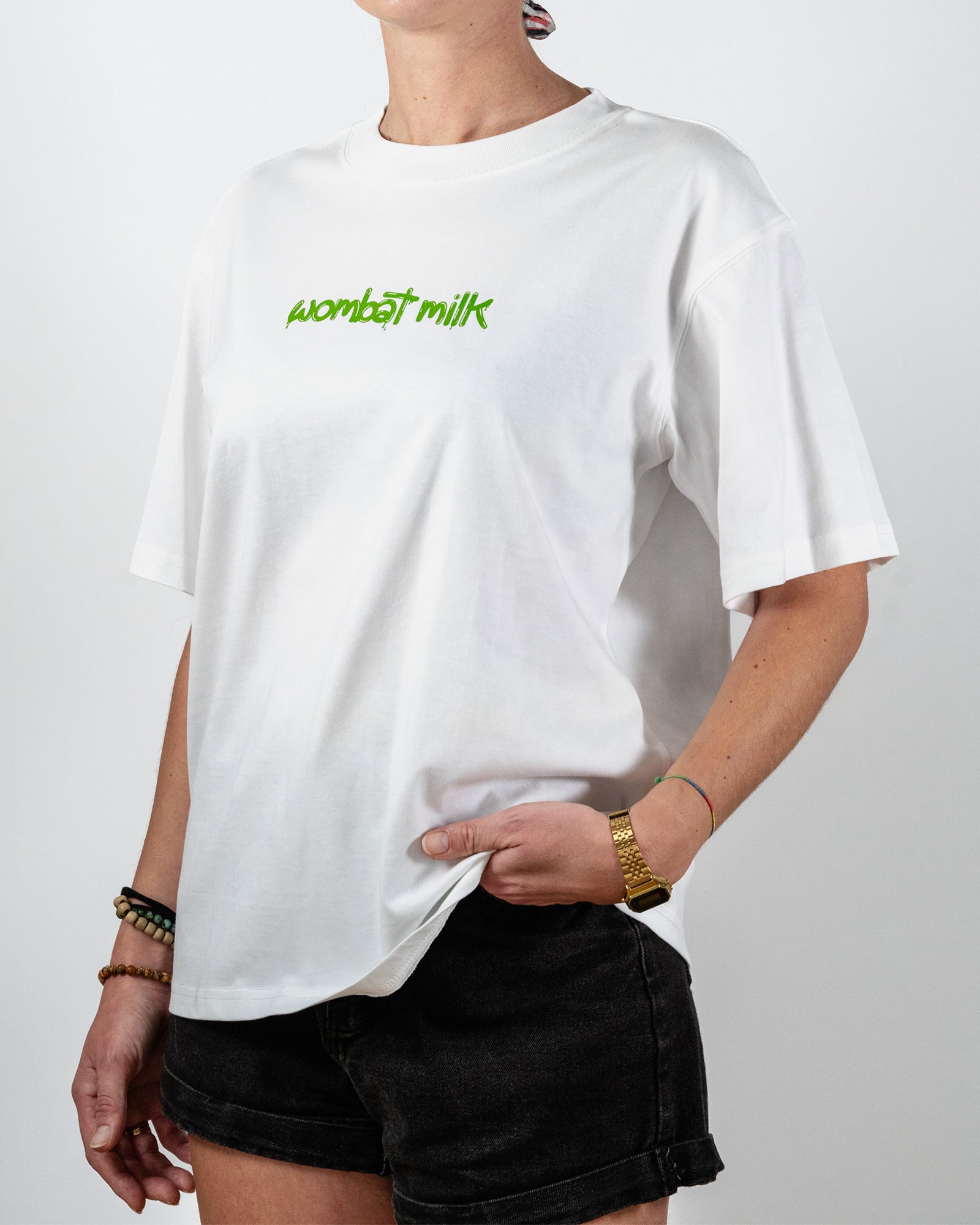 Person wearing a white t-shirt with 'wombat milk' text standing against a plain background.