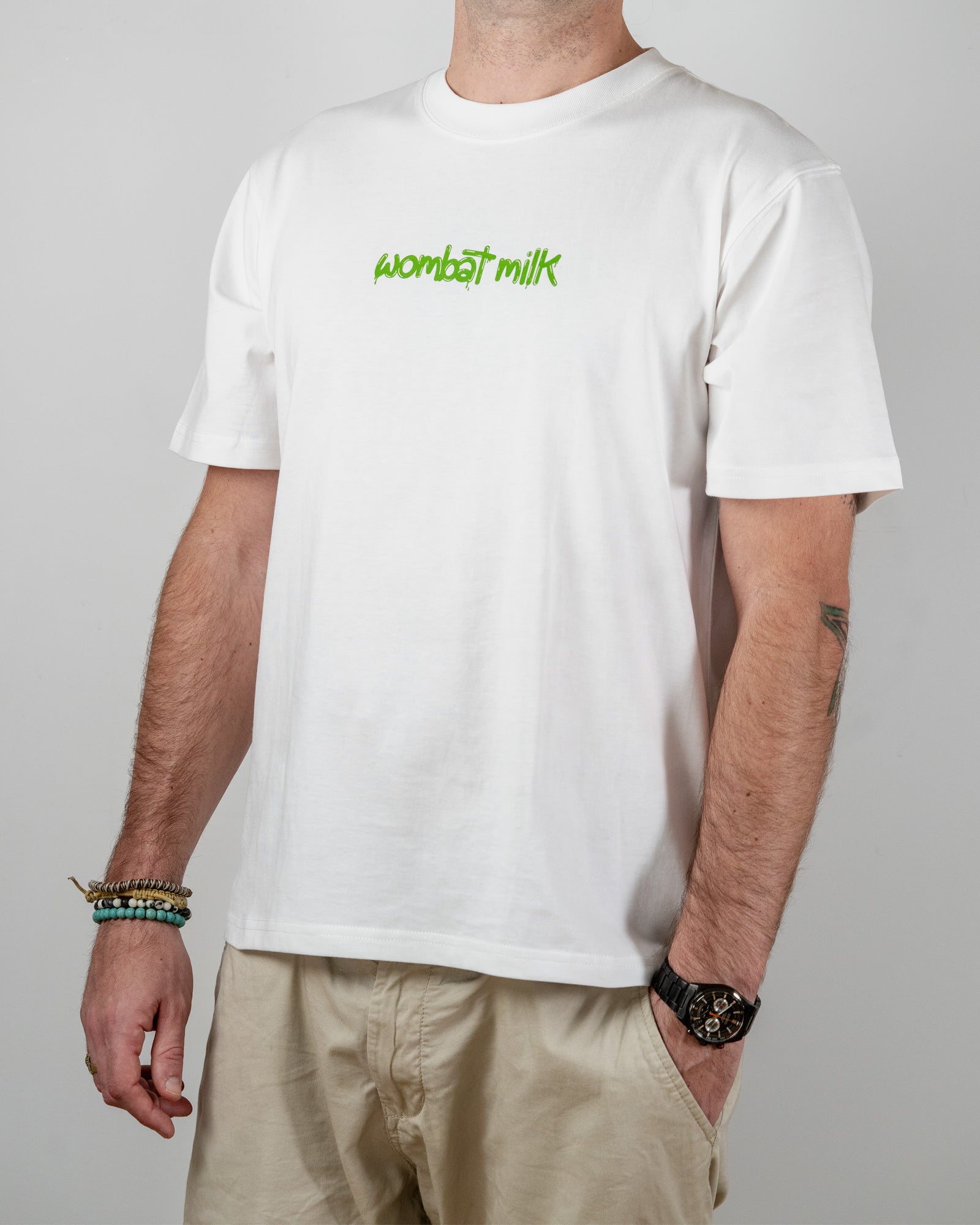 Person wearing a white t-shirt with 'wombat milk' text standing against a plain background.