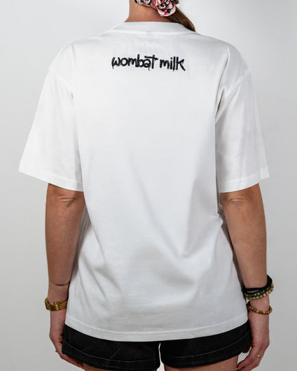 Person wearing a white t-shirt with 'wombat milk' text on the back against a plain background.
