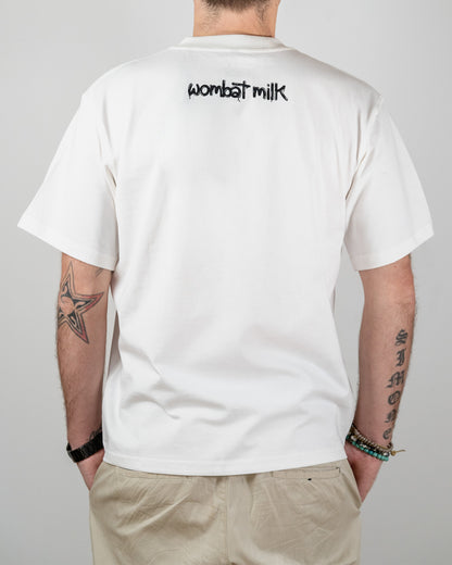 Person wearing a white t-shirt with 'wombat milk' text on the back, standing against a plain background.
