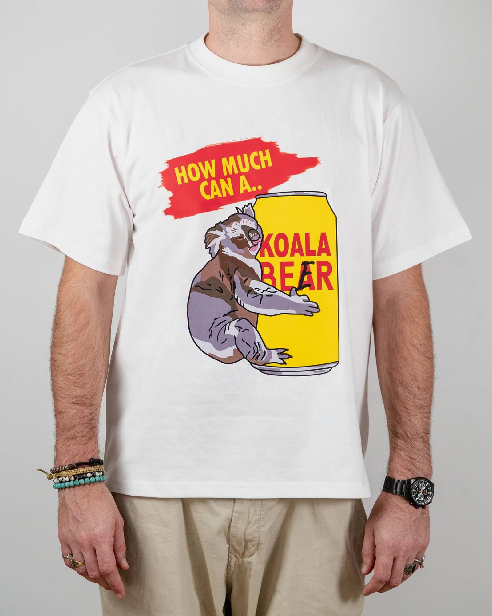Person wearing a white t-shirt with a koala bear graphic and text standing against a grey background.