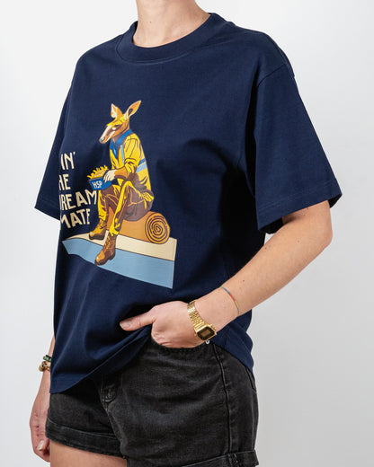 Navy blue t-shirt with a "Livin' The Dream Mate" graphic —featuring a kangaroo wearing a hi-vis set of overalls and work boots, eating an HSP kebab pack whilst sitting on a wooden log that is on top of a concrete slab.