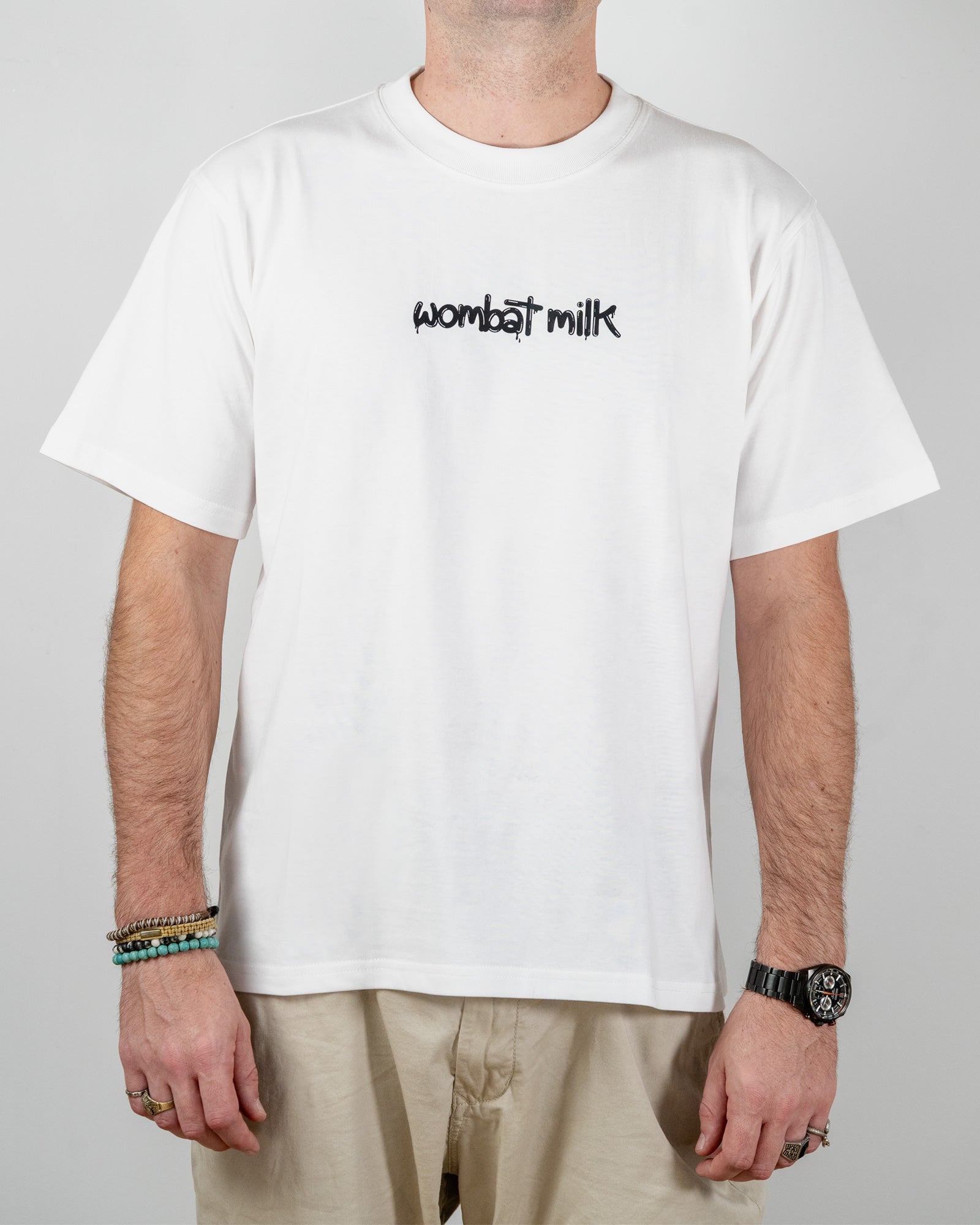 Person wearing a white t-shirt with 'wombat milk' text standing against a plain background.