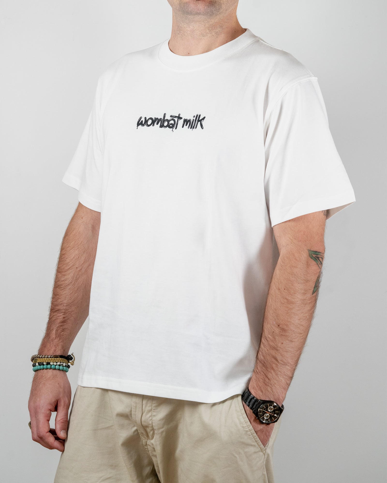 Person wearing a white t-shirt with 'wombat milk' text standing against a plain background.