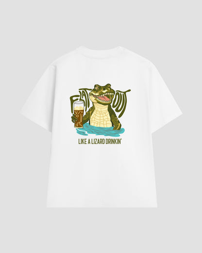 Unisex white t-shirt with a back print of the "Flat Out Like a Lizard Drinkin'" graphic — featuring a crocodile in a pool of water, holding a glass of beer and smiling with its mouth open, showing its teeth.